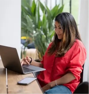a woman sitting at a table using a laptop computer