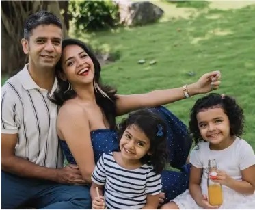 a man, woman and two children sitting on the grass