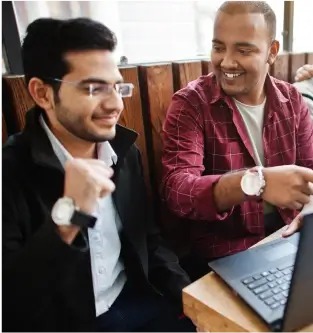 a couple of men sitting at a table with laptops