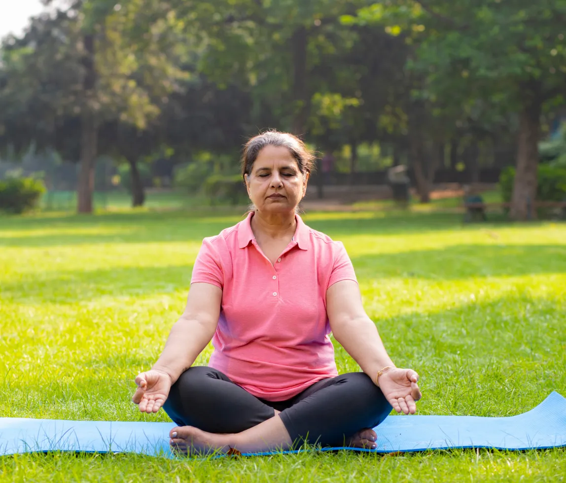 a woman in a pink shirt is sitting on a yoga mat
